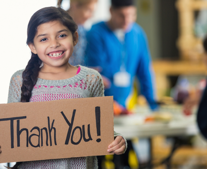 A young child holding a sign that says, "Thank You!"